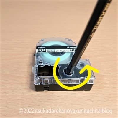 テープカートッリッジの損傷を防ぐためにテープカートッリッジの穴に鉛筆を差し込んで時計と逆方向に回してインクリボンのたるみを取っている画像です。